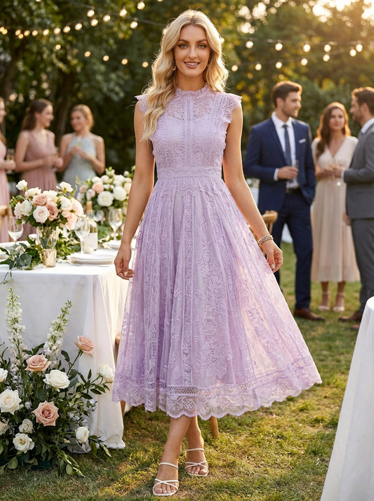 A woman wearing a lavender lace midi dress walks outdoors at a garden party. The dress has a high neck, cap sleeves, and a flared skirt with lace detailing.