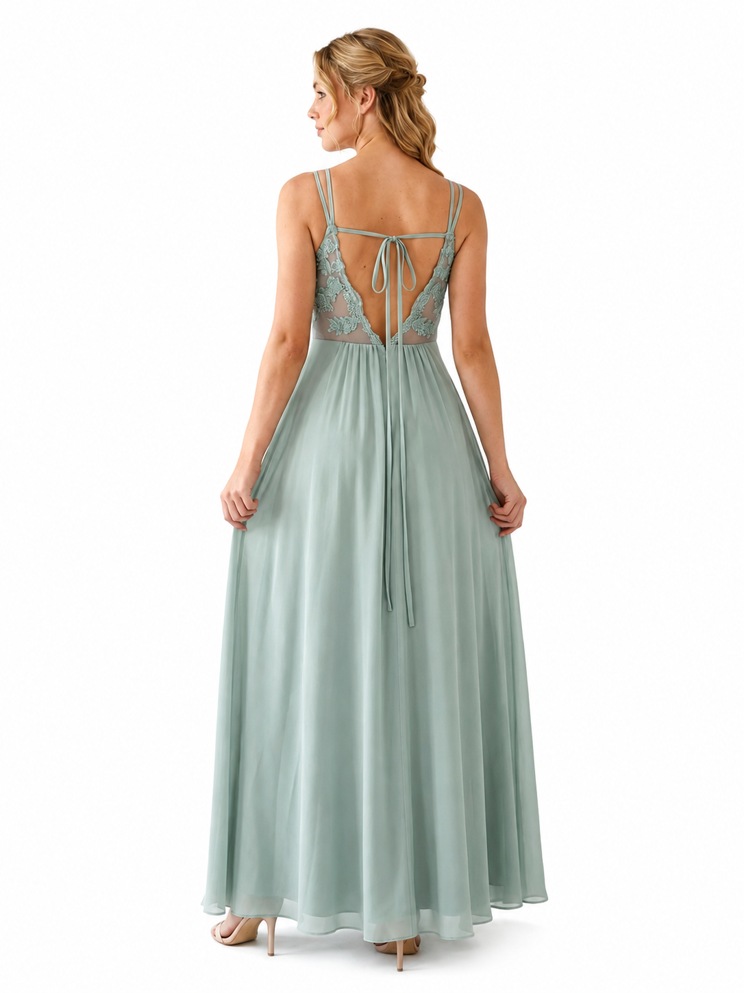 A woman modeling a floor-length sage green dress from the back, showing a lace open back with thin straps and a tie closure, on a plain white background.
